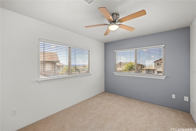 carpeted spare room featuring ceiling fan and plenty of natural light