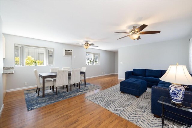 living room featuring hardwood / wood-style floors, a wall mounted air conditioner, and ceiling fan