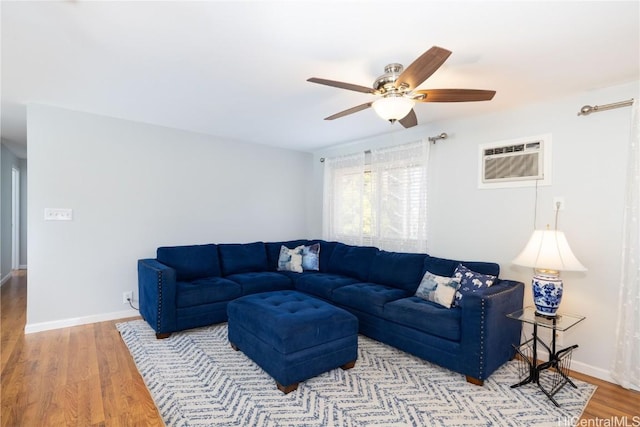 living room featuring a wall mounted air conditioner, light hardwood / wood-style flooring, and ceiling fan