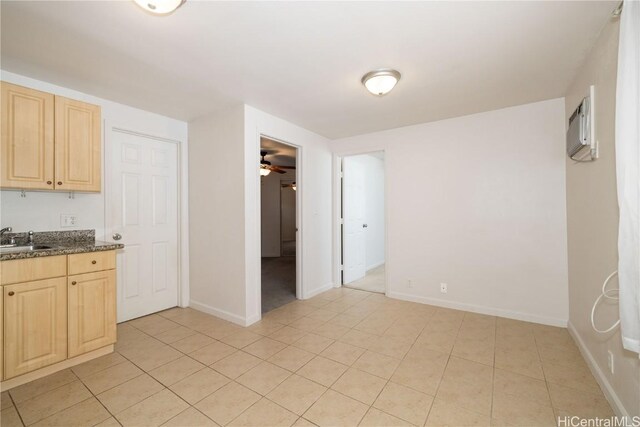 kitchen with light brown cabinetry, sink, a wall mounted AC, light tile patterned floors, and ceiling fan