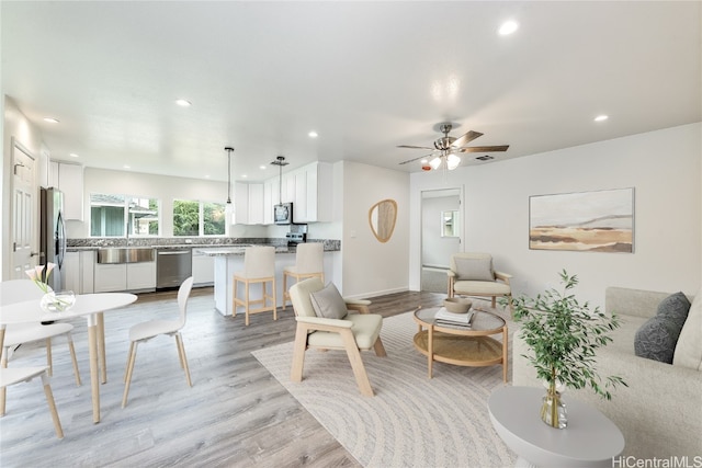 living room with light hardwood / wood-style flooring and ceiling fan