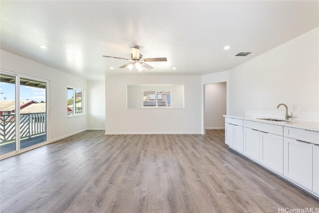 unfurnished living room featuring light wood-type flooring, ceiling fan, and sink