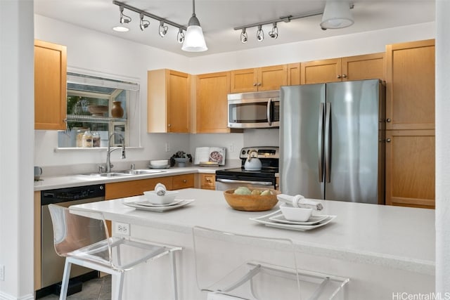 kitchen with a kitchen breakfast bar, sink, light brown cabinetry, decorative light fixtures, and stainless steel appliances