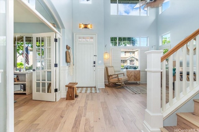 entryway featuring a high ceiling, stairs, hardwood / wood-style flooring, and a healthy amount of sunlight