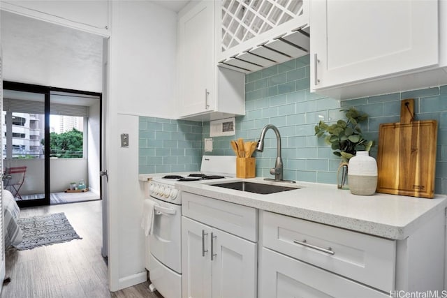 kitchen with backsplash, light stone counters, sink, white stove, and white cabinetry