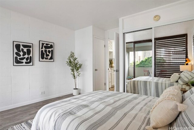 bedroom with access to outside, hardwood / wood-style flooring, and a closet