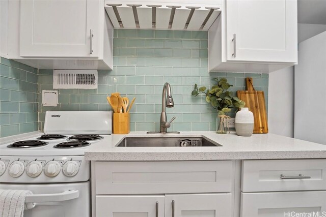 kitchen featuring tasteful backsplash, electric stove, white cabinetry, and sink