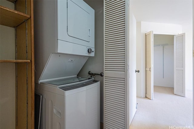 laundry room featuring stacked washer / dryer, light colored carpet, and laundry area