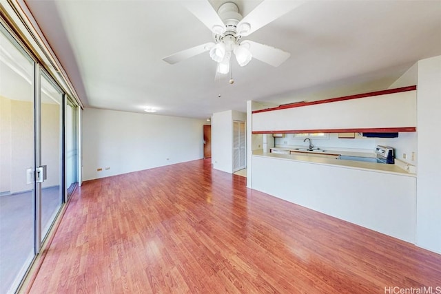 unfurnished living room featuring a sink, a ceiling fan, and light wood finished floors