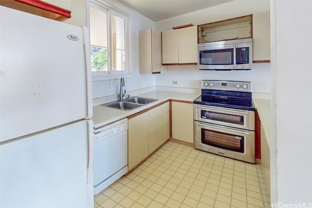 kitchen with light floors, a sink, stainless steel appliances, light countertops, and cream cabinets