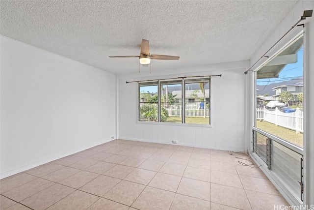 spare room featuring ceiling fan, plenty of natural light, and light tile patterned floors