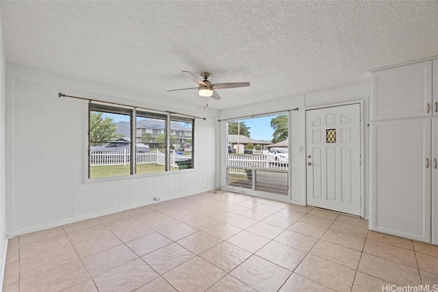 empty room with ceiling fan, light tile patterned flooring, and a textured ceiling