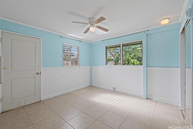 spare room with ceiling fan, a textured ceiling, plenty of natural light, and light tile patterned floors