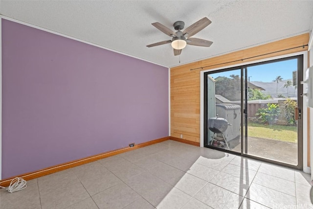 tiled empty room featuring a textured ceiling, ceiling fan, and wooden walls