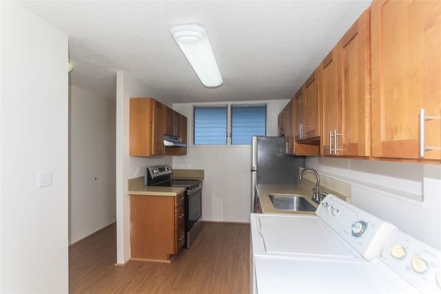 laundry room with a textured ceiling, laundry area, a sink, light wood-style floors, and washing machine and clothes dryer