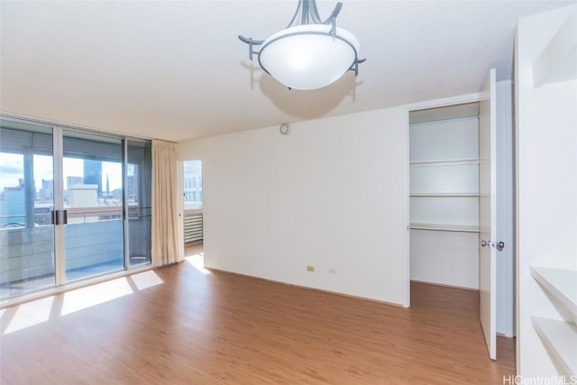 unfurnished room with wood finished floors and floor to ceiling windows