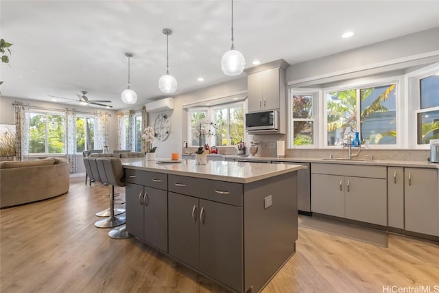 kitchen with a kitchen island, gray cabinetry, hanging light fixtures, and stainless steel appliances