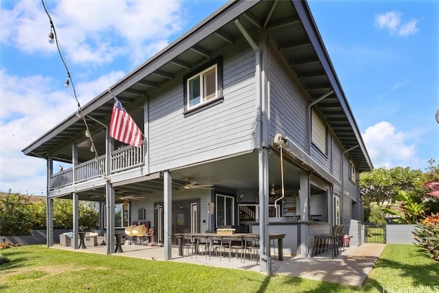 back of house featuring ceiling fan, a patio, a lawn, and a balcony