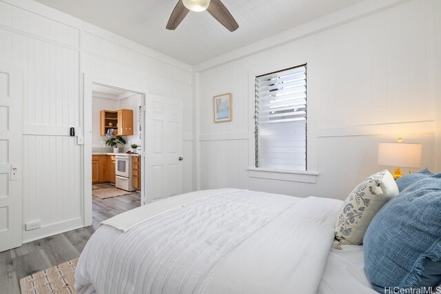 bedroom featuring ceiling fan, ensuite bath, and wood finished floors