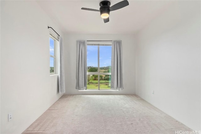 spare room featuring light carpet, ceiling fan, and a healthy amount of sunlight