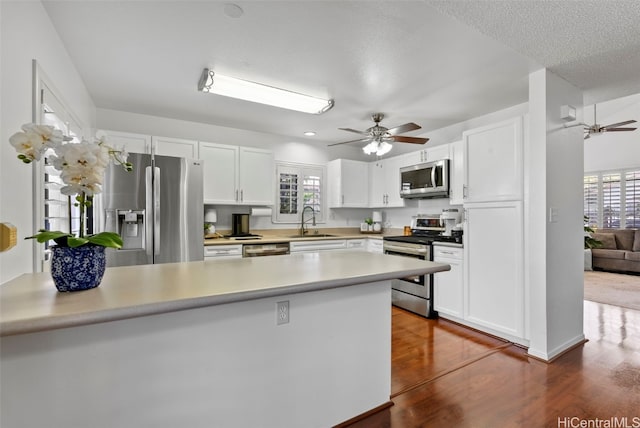 kitchen featuring kitchen peninsula, sink, white cabinetry, and stainless steel appliances