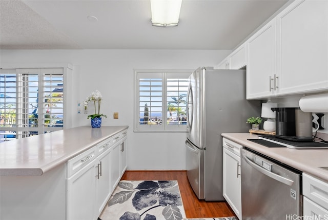 kitchen with light hardwood / wood-style floors, white cabinetry, kitchen peninsula, and appliances with stainless steel finishes