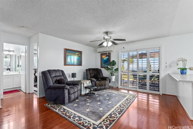 living room featuring ceiling fan, wood-type flooring, a textured ceiling, and a wall unit AC