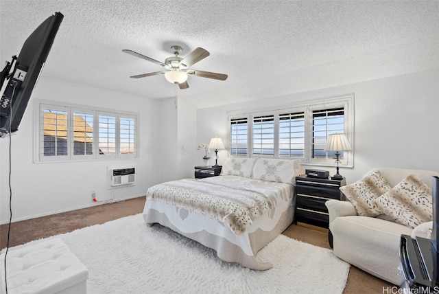 carpeted bedroom featuring a wall mounted AC, a textured ceiling, multiple windows, and ceiling fan