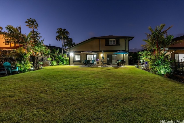 back house at dusk with a lawn