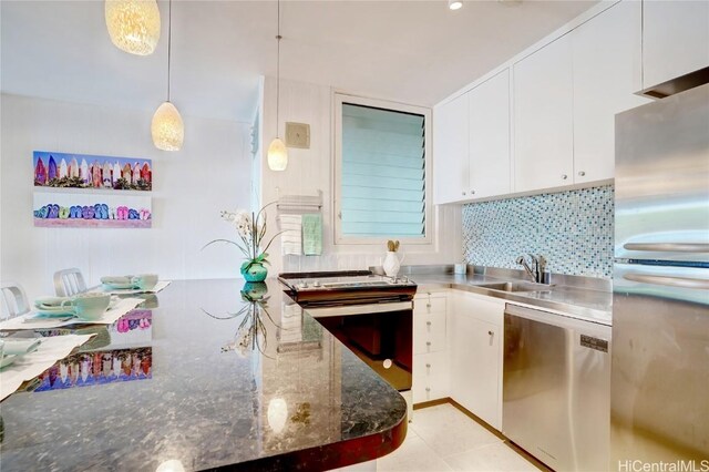 kitchen featuring pendant lighting, backsplash, sink, white cabinetry, and stainless steel appliances