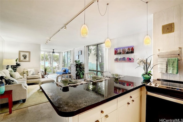 kitchen with rail lighting, decorative light fixtures, dark stone countertops, white cabinets, and range with electric stovetop