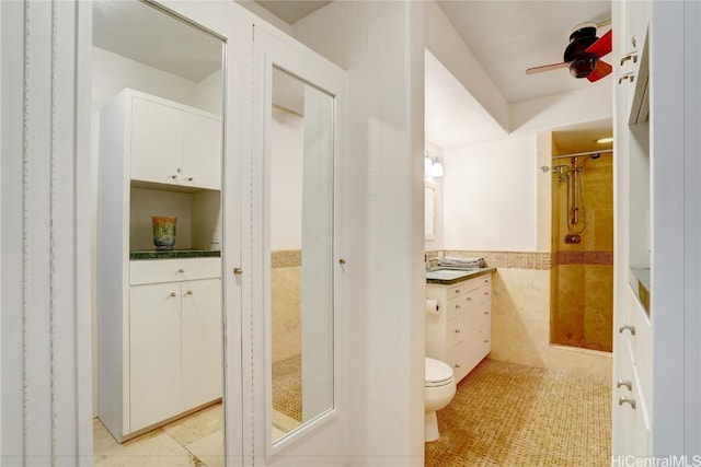 bathroom with vanity, ceiling fan, tile walls, tile patterned flooring, and toilet