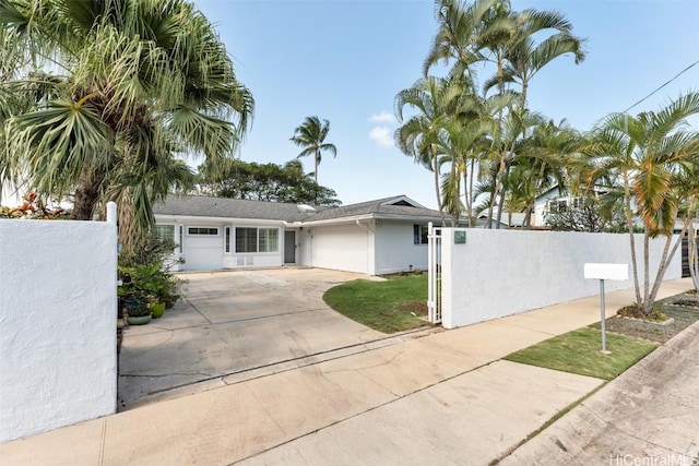 ranch-style home featuring a fenced front yard, a garage, driveway, and stucco siding