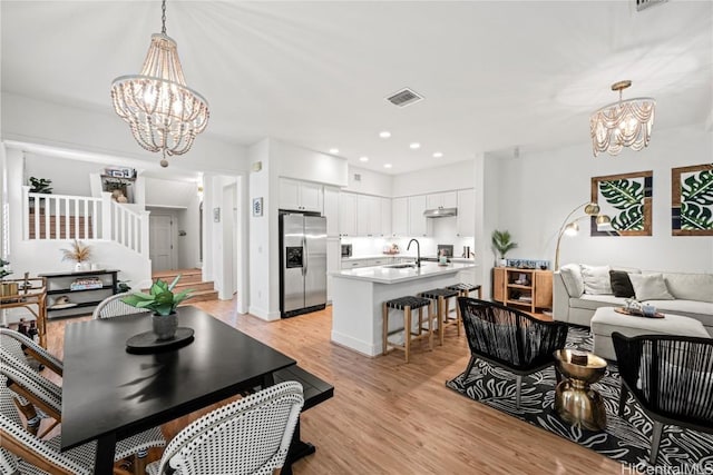 dining area with an inviting chandelier, sink, and light hardwood / wood-style floors