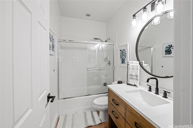 full bathroom with enclosed tub / shower combo, vanity, and toilet