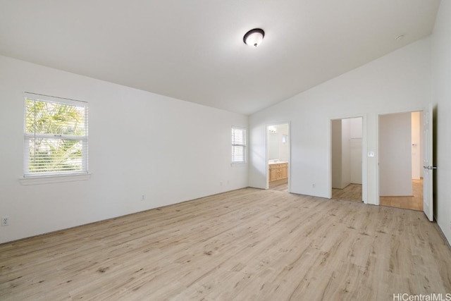 unfurnished bedroom with light wood-type flooring, ensuite bathroom, multiple windows, and lofted ceiling