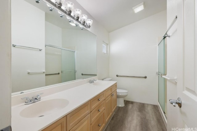 bathroom featuring wood-type flooring, vanity, toilet, and a shower with shower door