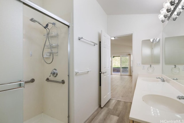 bathroom featuring hardwood / wood-style floors, vanity, vaulted ceiling, and a shower with shower door