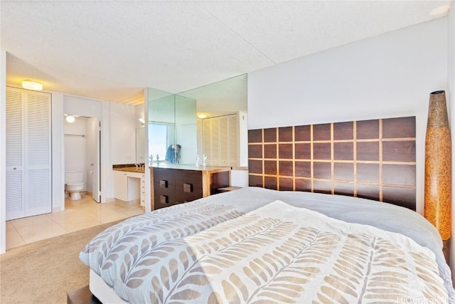 bedroom featuring a textured ceiling, carpet floors, and ensuite bath