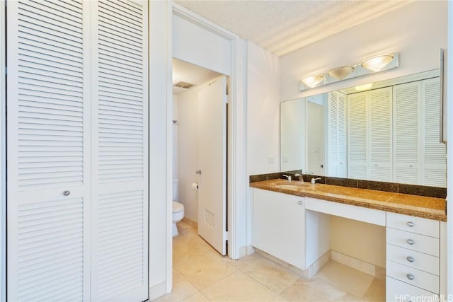 bathroom featuring toilet, vanity, tile patterned flooring, and a textured ceiling