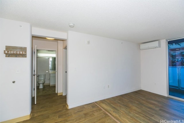 spare room with a textured ceiling, dark wood-type flooring, and a wall mounted AC