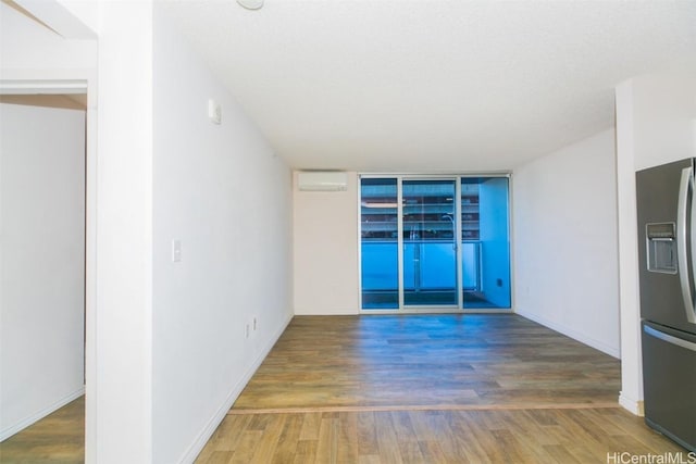 spare room featuring a wall mounted air conditioner and wood-type flooring