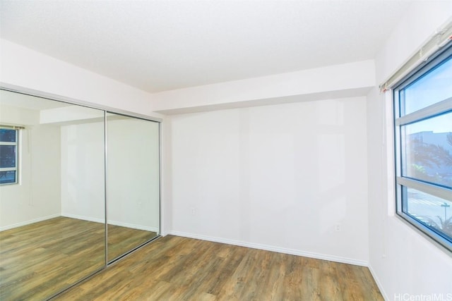 unfurnished bedroom featuring dark hardwood / wood-style flooring and a closet