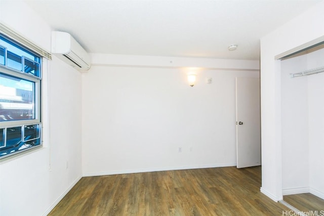 spare room with an AC wall unit and dark hardwood / wood-style flooring