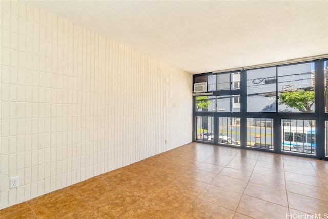 unfurnished room with a textured ceiling, tile patterned floors, and expansive windows