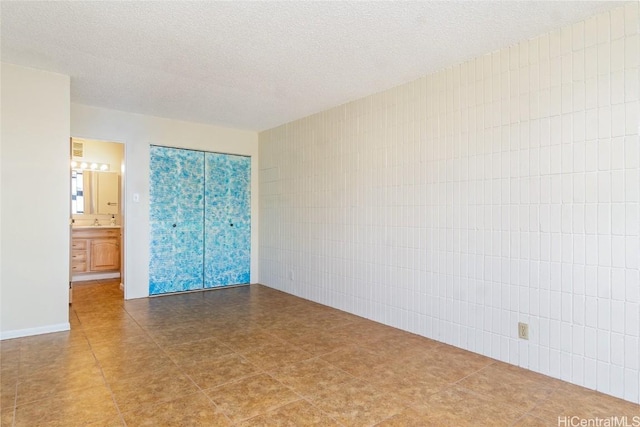 interior space with tile walls, ensuite bathroom, and a textured ceiling