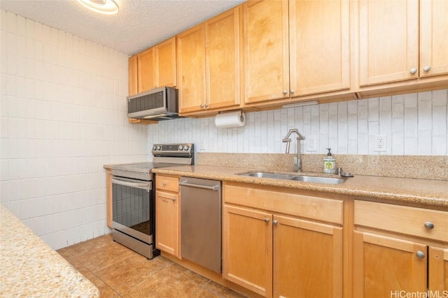 kitchen with a textured ceiling, sink, light tile patterned floors, and stainless steel appliances