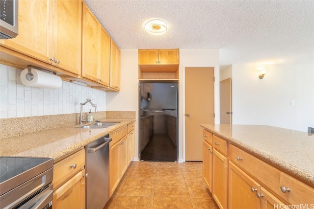 kitchen with dishwasher, black fridge, sink, light stone countertops, and a textured ceiling