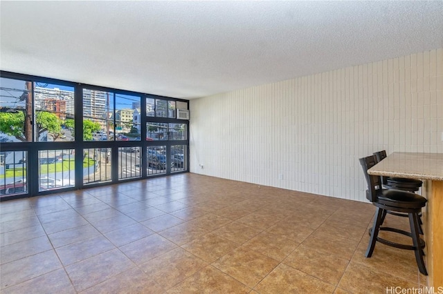 unfurnished room featuring a wall of windows, a textured ceiling, and light tile patterned floors