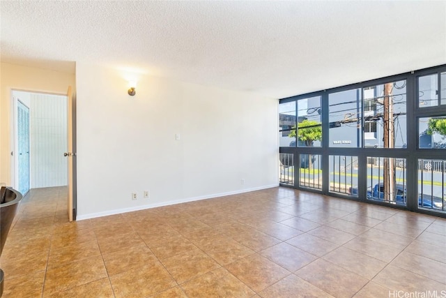 empty room featuring a wall of windows, a textured ceiling, and light tile patterned floors